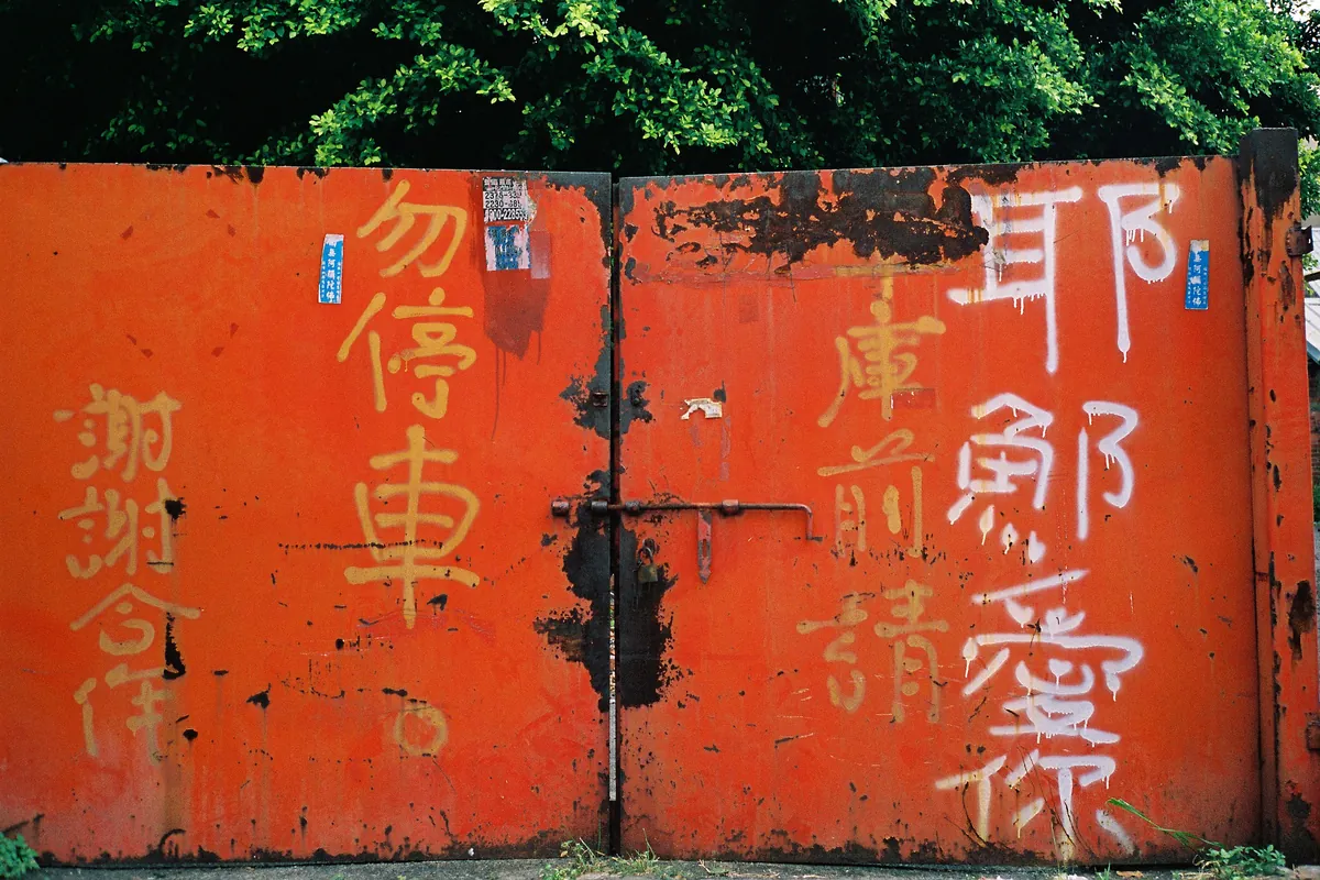 Shot on Contax T2: A weathered red garage door painted with white Chinese characters