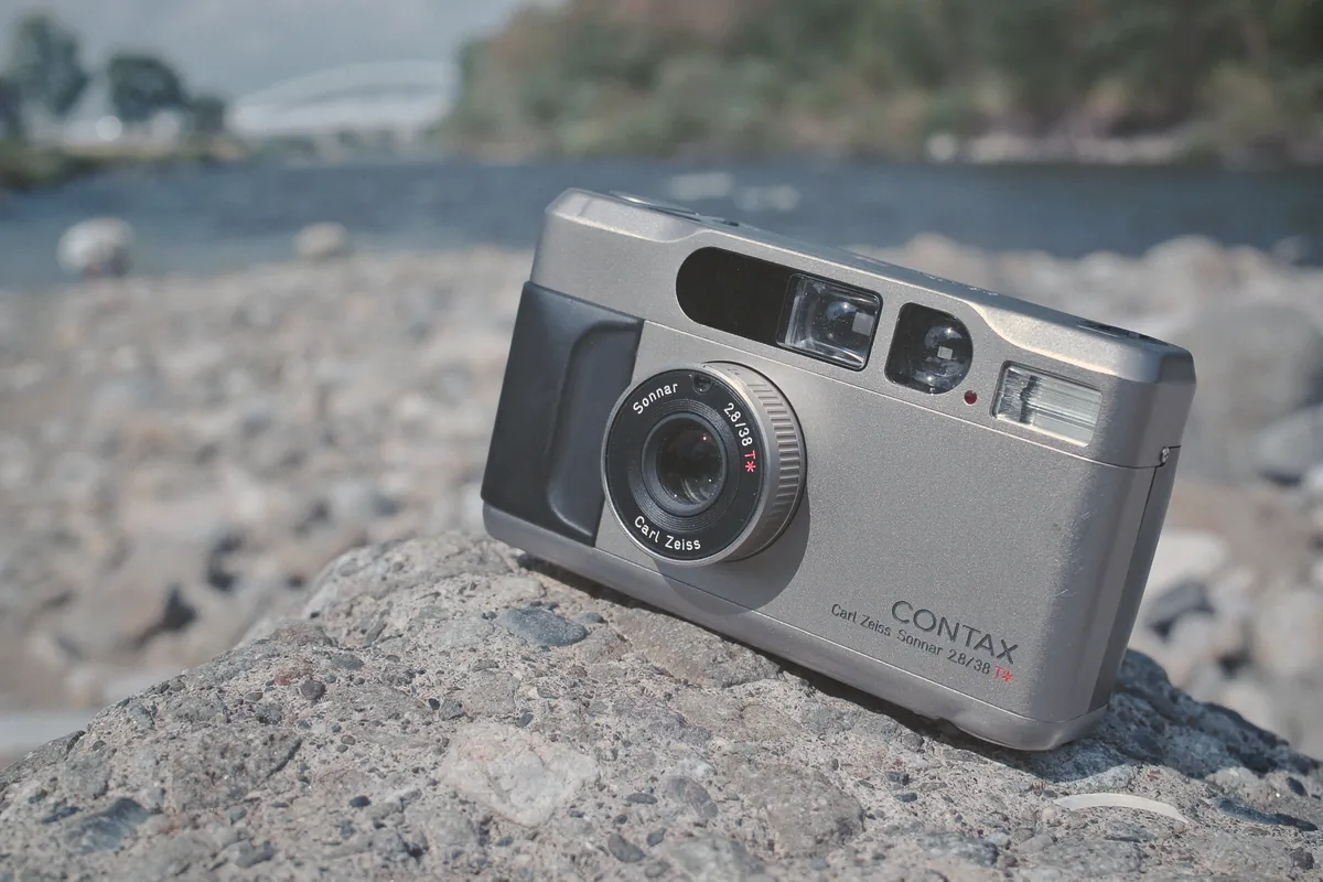 Contax T2: a titanium Contax T2 with its lens out, sitting on a rock by a river